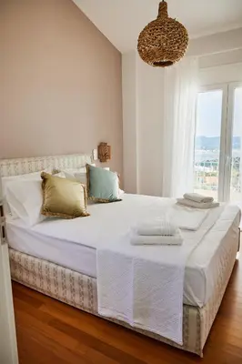 a white bedroom with a large bed with a chandelier at Athens Riviera Villa in Anavissos