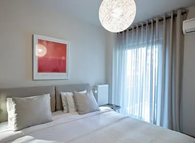 a bedroom with a white bed with a large window at Athenian Riviera Exclusive flat , Athens Greece in Athens