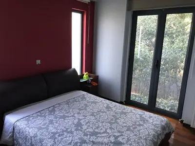 a bedroom with a bed and two large windows at Mina’s Villa, 200m from the beach in Porto Rafti