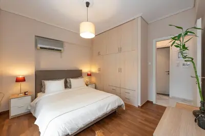 a bedroom with a large white bed and wooden floors at Cozy 1Bdrm Apt/walk to the beach in Athens