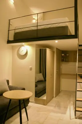 a loft bed in a room with a couch and a table at Piraeus Relax in Piraeus