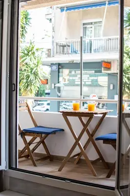 a table and chairs on a balcony with a window at ARIS Ampelokipoi in Athens
