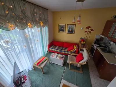 a living room with a red couch and a kitchen at Pela's studio 10 minutes from the Athens airport in Leondárion