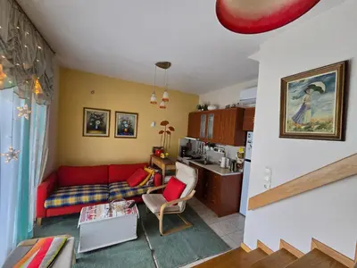a living room with a red couch and a kitchen at Pela's studio 10 minutes from the Athens airport in Leondárion