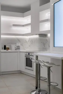 a kitchen with white cabinets and a counter with stools at Acropolis Museum Apartment by A&A Residences in Athens