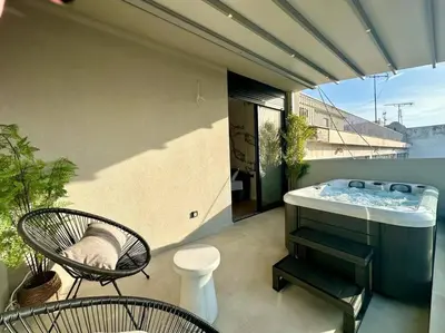 a balcony with a tub and a chair and a table at BlueMotion - SensaBlu in Piraeus