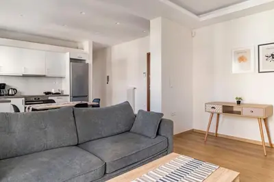 a living room with a gray couch and a kitchen at Alimos Seabreeze apartment in Athens