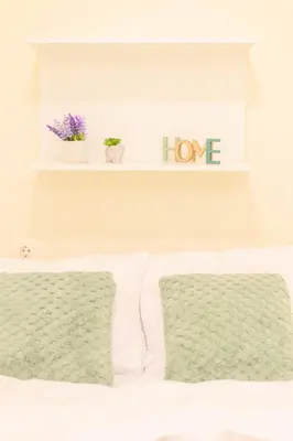 a bed with two pillows and a shelf with love at Aiolos GLYFADA luxury apartment in Athens