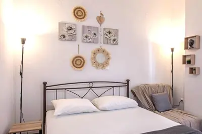 a bedroom with a bed with white sheets and pictures on the wall at Minimal and cozy Home in Zografou in Athens