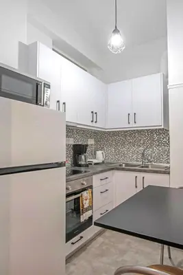 a kitchen with white cabinets and a black counter top at Minimal and cozy Home in Zografou in Athens