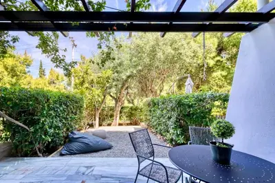 a patio with a table and chairs and trees at The Four Seasons Vouliagmeni Escape in Athens