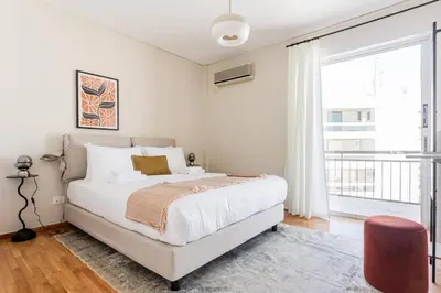 a white bedroom with a bed and a large window at Exclusive 2BR Apartment in Alimos by UPSTREET in Athens