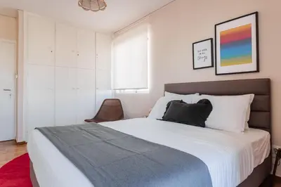 a bedroom with a large bed and a chair at Exclusive 2BR Apartment in Alimos by UPSTREET in Athens