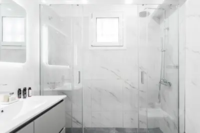 a white bathroom with a shower and a sink at Exclusive 2BR Apartment in Alimos by UPSTREET in Athens