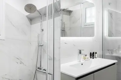 a white bathroom with a sink and a shower at Exclusive 2BR Apartment in Alimos by UPSTREET in Athens