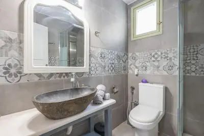 a bathroom with a stone sink and a toilet at Διαμέρισμα με πισίνα στην Αρτέμιδα in Vravrona