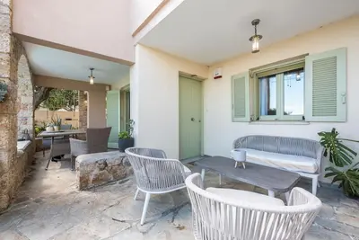 a patio with white chairs and a table and a table and chairs at Διαμέρισμα με πισίνα στην Αρτέμιδα in Vravrona