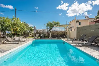 a swimming pool with blue water in a yard at Διαμέρισμα με πισίνα στην Αρτέμιδα in Vravrona