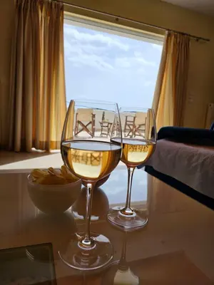 two glasses of wine sitting on a table in front of a window at Zoe's home - stunning view in Áyios Konstandínos