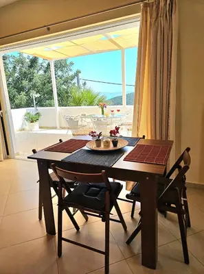 a dining room table with chairs and a large window at Zoe's home - stunning view in Áyios Konstandínos