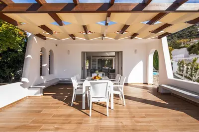 a patio with a white table and chairs and a wooden ceiling at Astarte Sunset Villa in Sounio