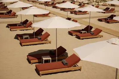 a bunch of lounge chairs and umbrellas on a beach at 91 Athens Riviera, The Resort in Athens
