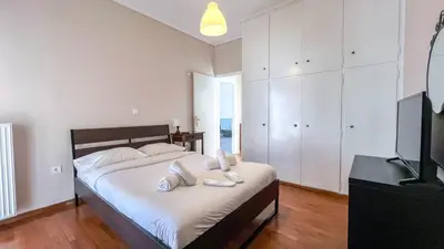 a bedroom with a bed with white sheets and a television at Alimos Sea View Family Apartment in Athens