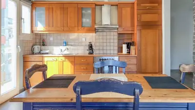 a kitchen with a wooden table with two chairs and a tableablish at Alimos Sea View Family Apartment in Athens