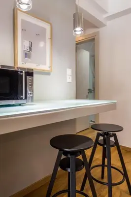 a kitchen with two stools and a counter with a microwave at Elegance Vouliagmeni Gem Luxury Apt, Walk to Beach in Athens
