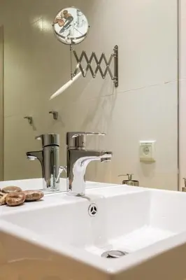 a bathroom sink with a faucet and a mirror at Elegance Vouliagmeni Gem Luxury Apt, Walk to Beach in Athens