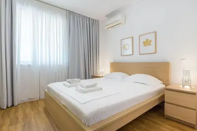 a bedroom with a bed with white sheets and a window at Elegance Vouliagmeni Gem Luxury Apt, Walk to Beach in Athens