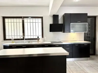 a kitchen with black cabinets and a white counter top at Glyfada Grand Residence in Athens
