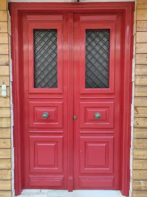 a red door with two windows on a house at Page55 in Piraeus