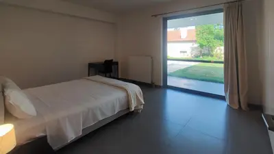 a bedroom with a bed and a large sliding glass door at ΒΙΛΑ ΜΕ ΠΙΣΙΝΑ ΣΤΗΝ ΠΑΙΑΝΙΑ in Paianía