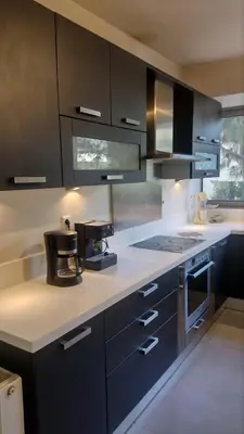 a kitchen with black cabinets and a white counter top at ΒΙΛΑ ΜΕ ΠΙΣΙΝΑ ΣΤΗΝ ΠΑΙΑΝΙΑ in Paianía