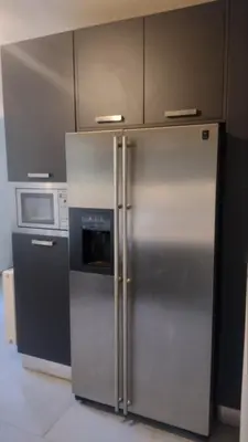 a kitchen with a stainless steel refrigerator and a microwave at ΒΙΛΑ ΜΕ ΠΙΣΙΝΑ ΣΤΗΝ ΠΑΙΑΝΙΑ in Paianía