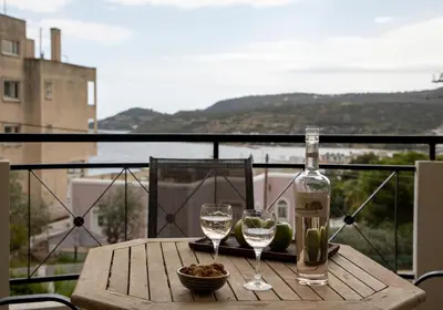 a table with two glasses of wine on a balcony at Anesis Apartments in Agia Marina Aegina