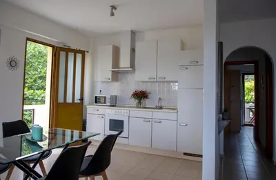 a kitchen with white cabinets and a glass table at Anesis Apartments in Agia Marina Aegina