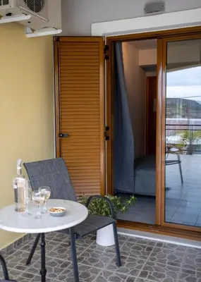a patio with a table and a chair and a patio door at Anesis Apartments in Agia Marina Aegina