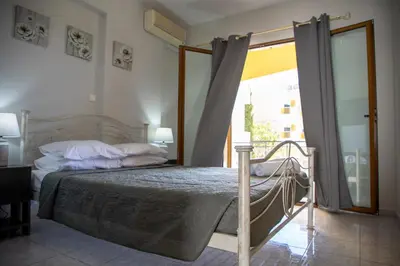 a bedroom with a bed and a sliding glass door at Anesis Apartments in Agia Marina Aegina
