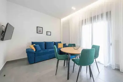 a living room with a blue couch and a table and chairs at Cozy apartment in a new building apartment 2 in Piraeus