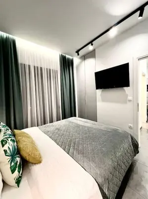 a bedroom with a bed and a flat screen tv at Cozy apartment in a new building apartment 3 in Piraeus