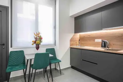 a kitchen with a table and four green chairs at Cozy apartment in a new building apartment 4 in Piraeus