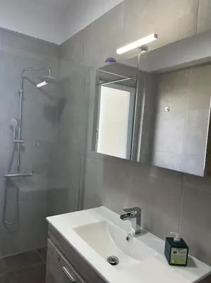 a bathroom with a sink and a shower and a mirror at Glyfada 3 Bed: Modern & Cozy in Athens