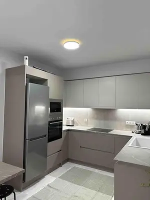 a kitchen with white cabinets and a stainless steel refrigerator at Glyfada 3 Bed: Modern & Cozy in Athens