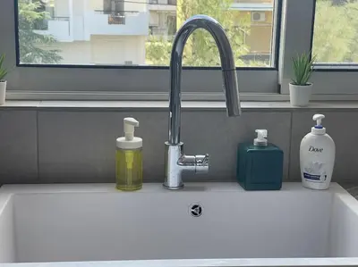 a white kitchen sink with a sink at Glyfada 3 Bed: Modern & Cozy in Athens