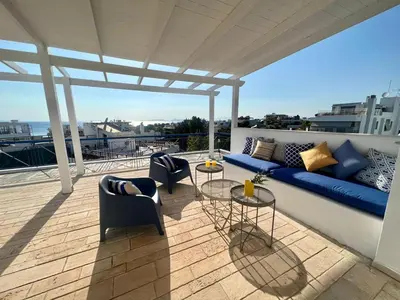 a patio with a blue couch and chairs on a balcony at Voula Panoramic Terraces - Greecing in Athens