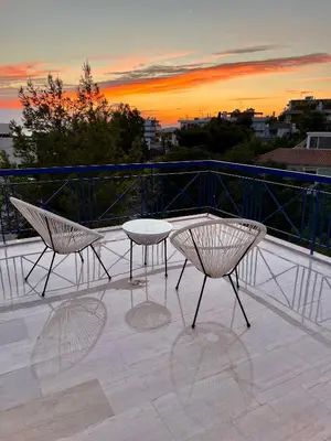 a table and chairs on a balcony with a sunset at Voula Panoramic Terraces - Greecing in Athens