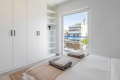 a white bedroom with a bed and a large window at Voula Panoramic Terraces - Greecing in Athens