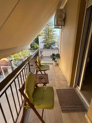a balcony with two green chairs and a window at Sunshine Bliss Apartment in Athens